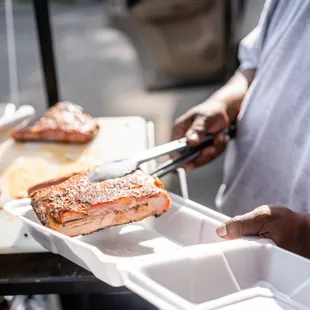 a man holding a tray of ribs