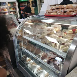 a woman looking at pastries in a display case