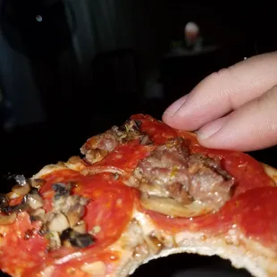 a hand holding a slice of pizza