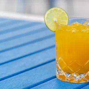 a glass of orange juice on a blue table