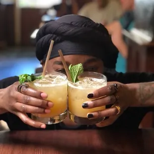 a woman holding two glasses of cocktail