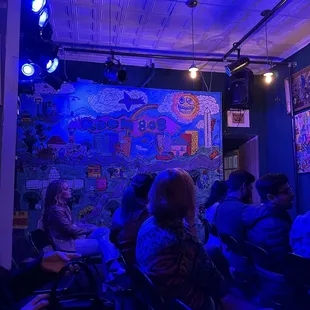 people sitting in chairs in front of a colorful mural