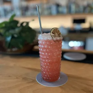 a pink drink with a straw and a lemon garnish