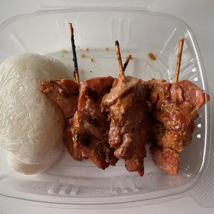 skewered meat and rice in a plastic container