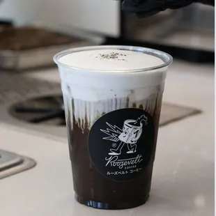 Black Widow Iced Americano made with Crown Point Espresso and black sesame, capped off with black sesame cold foammmmm.