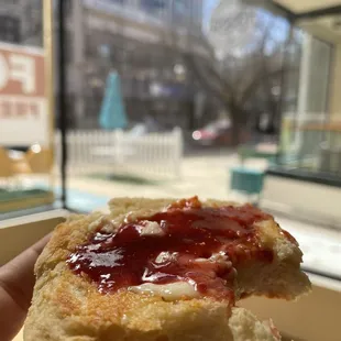 a hand holding a pastry with jam on it