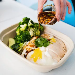 a person pouring sauce over a meal