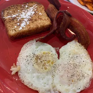 a plate of eggs, toast, and bacon