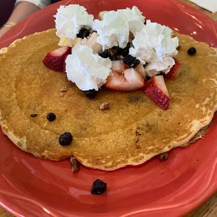 a stack of pancakes with whipped cream and strawberries