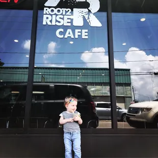 a little boy standing in front of a cafe