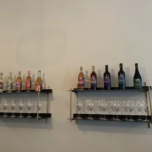 two shelves with wine glasses and wine bottles