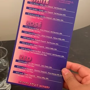 a hand holding a wine selection menu