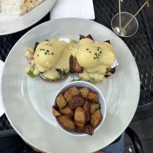 a plate of food with eggs benedict and potatoes