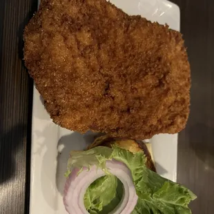 a fried chicken sandwich with lettuce and onion
