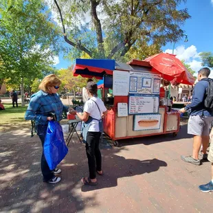 a group of people standing around a food cart