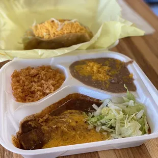 My meal with cheese enchilada, beans and rice. The chicken taco is on yellow paper.