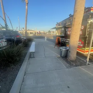 a view of a sidewalk with trash cans