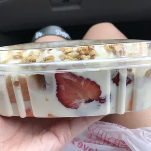 a hand holding a container of yogurt