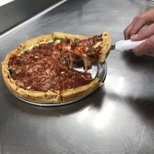 a person cutting a deep dish pizza
