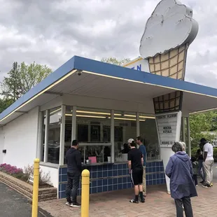 a group of people standing in front of the ice cream shop