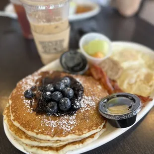 a plate of pancakes with blueberries and bacon