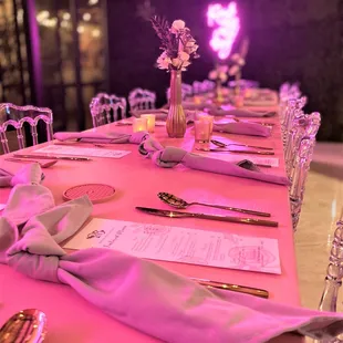 a pink table setting with silver cutlers and napkins