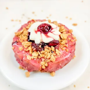 a pink donut with cranberries and granola