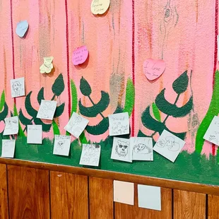 a pink wall with lots of notes on it