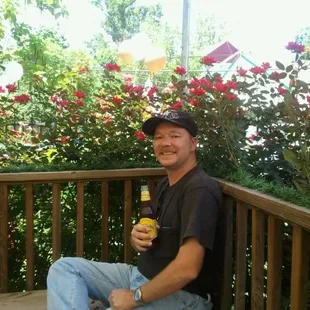 a man sitting on a porch holding a bottle of beer