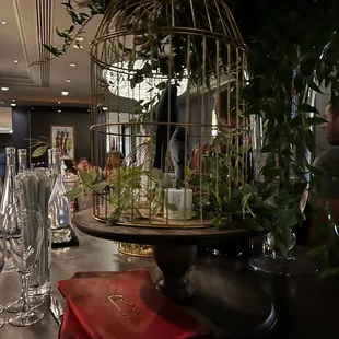 a birdcage filled with flowers and greenery