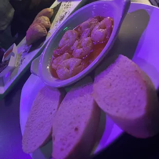 a bowl of shrimp and bread on a plate