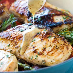 a spoon drizzling sauce over chicken breasts