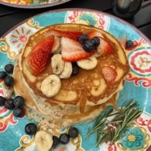 a stack of pancakes with berries and bananas