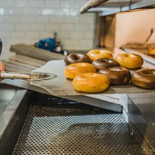 a baker holding a spatula in front of a tray of doughnuts