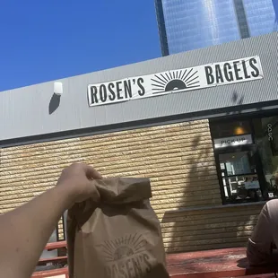 a person holding a bag of bagels