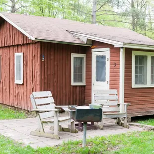 a red cabin with two chairs and a grill