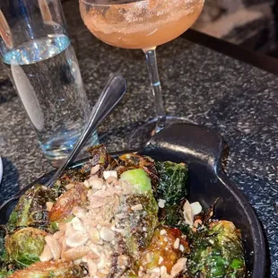 a plate of brussel sprouts and a glass of wine