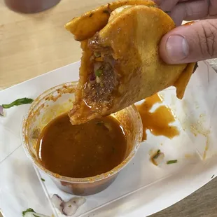 a person dipping sauce into a sandwich