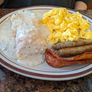Biscuits and gravy with eggs, sausage and bacon.