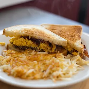 a breakfast sandwich and hash browns on a plate