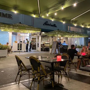 people sitting at tables outside a restaurant