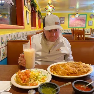 a man sitting at a table with plates of food and a drink