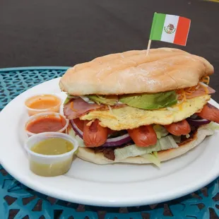 Torta Cubana- Grilled Mexican bread w/Carne Asada, Ham, Grilled Hot Dogs, Fried Egg, lettuce, onions, cheese, avocado, jalapenos, and mayo