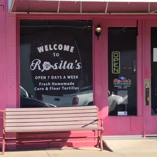 a bench in front of a pink building