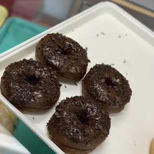 three chocolate donuts on a plate