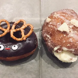 two donuts with chocolate frosting and pretzels