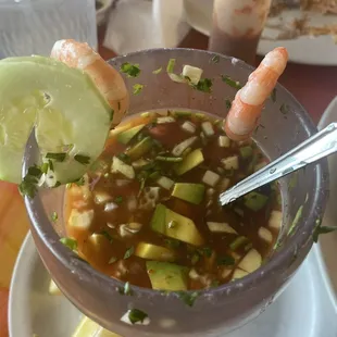 a bowl of soup with shrimp and avocado