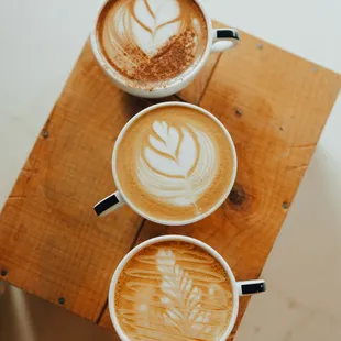 three cups of coffee on a wooden table