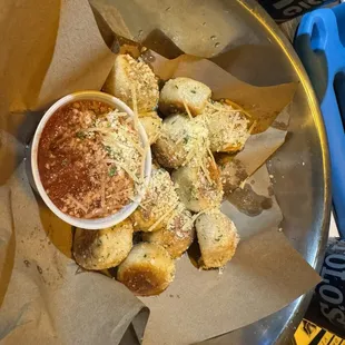 a bowl of sauce and breadsticks