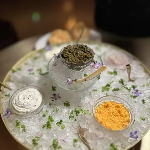 a bowl of caviate on ice with spoons